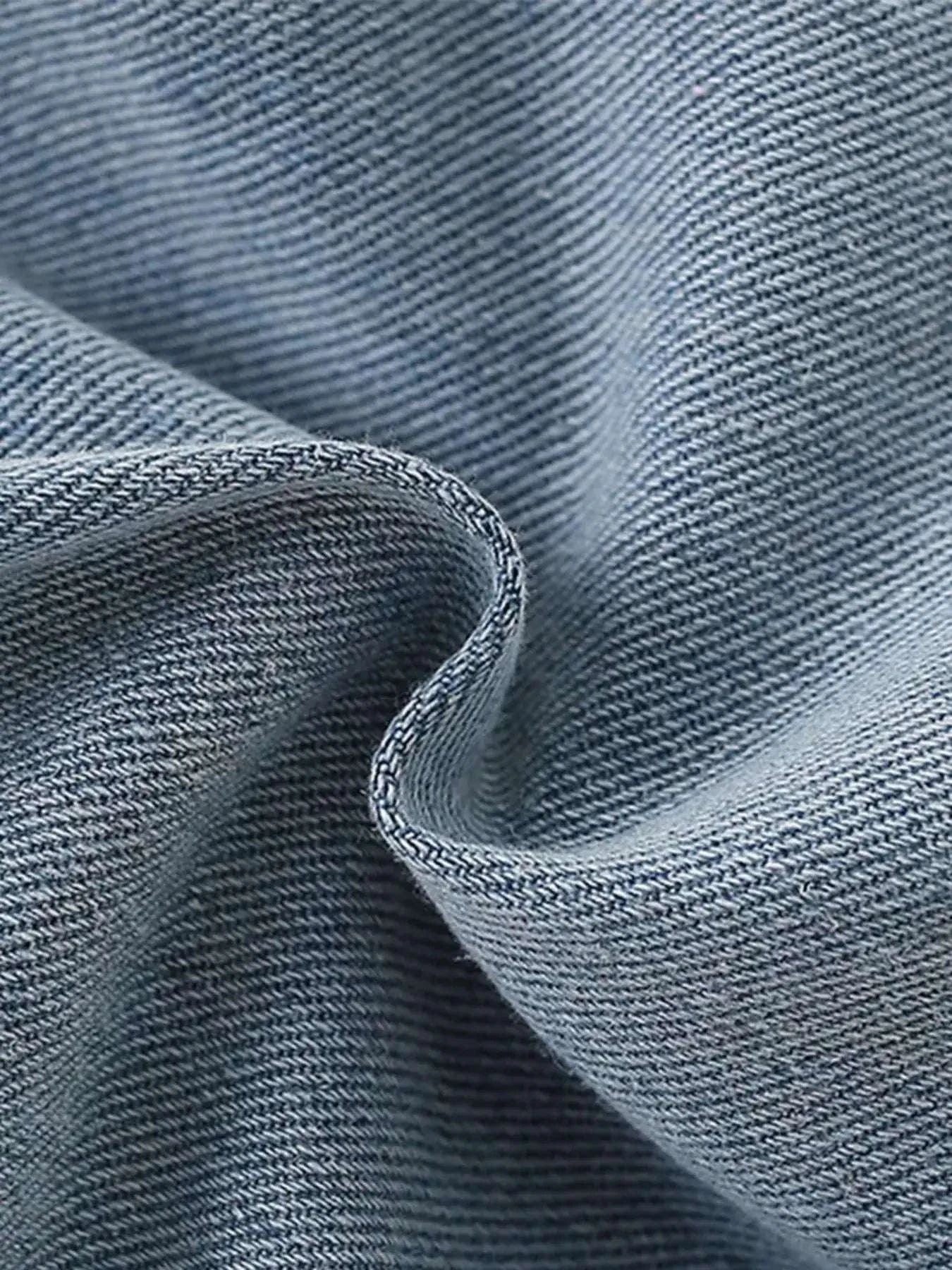 Denim shorts fabric close-up with textured blue twill weave and stitched seam edge