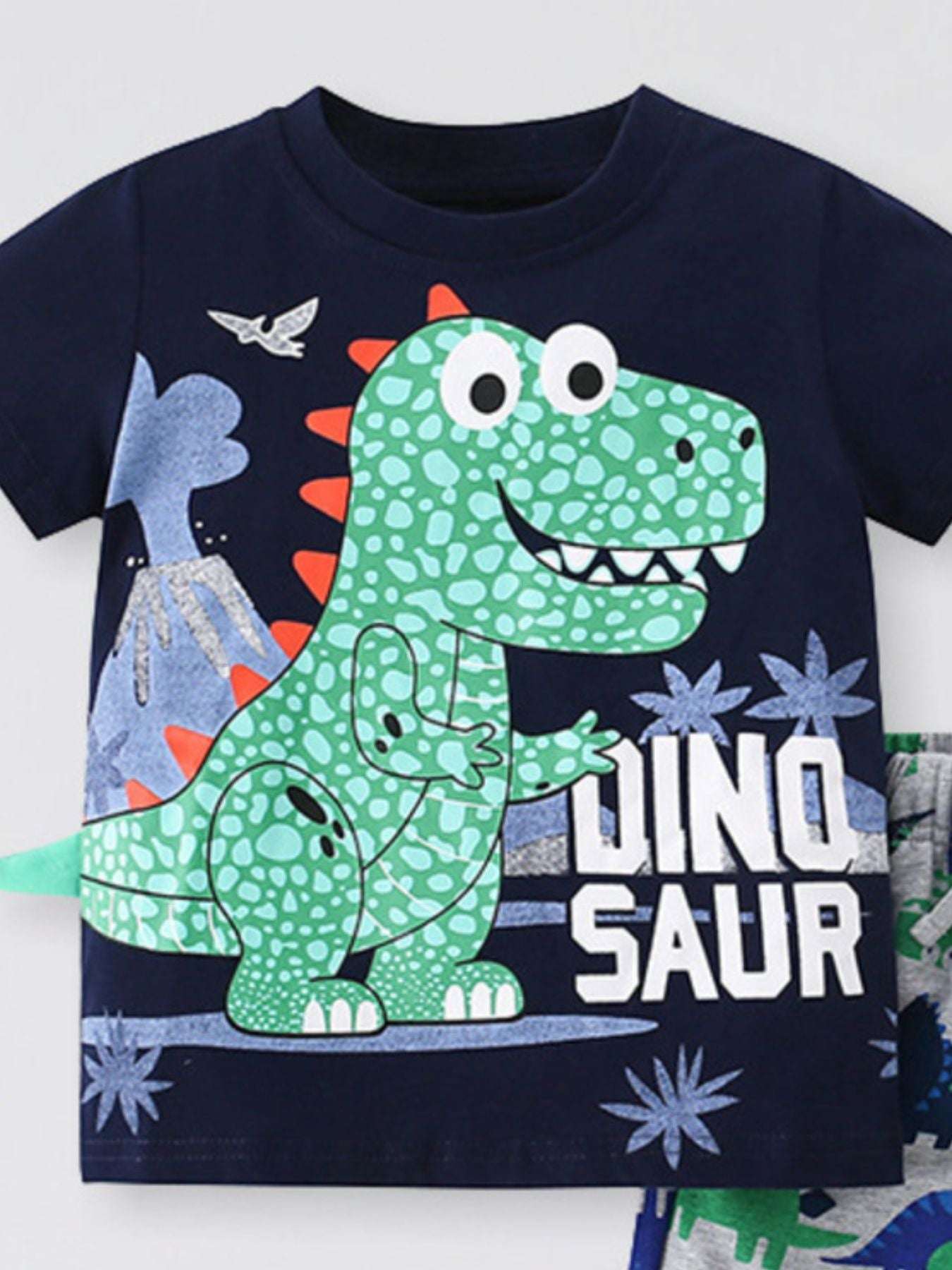 Kids navy dino graphic short sleeve tee with large green dinosaur face; shorts partly visible