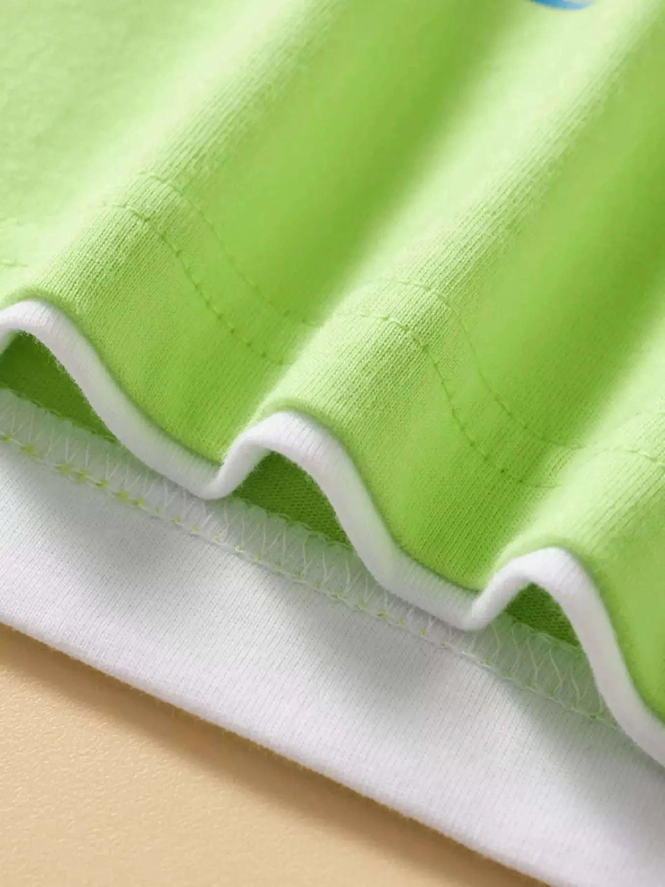 Neon green kids T-shirt hem with visible stitching and white ribbed underside