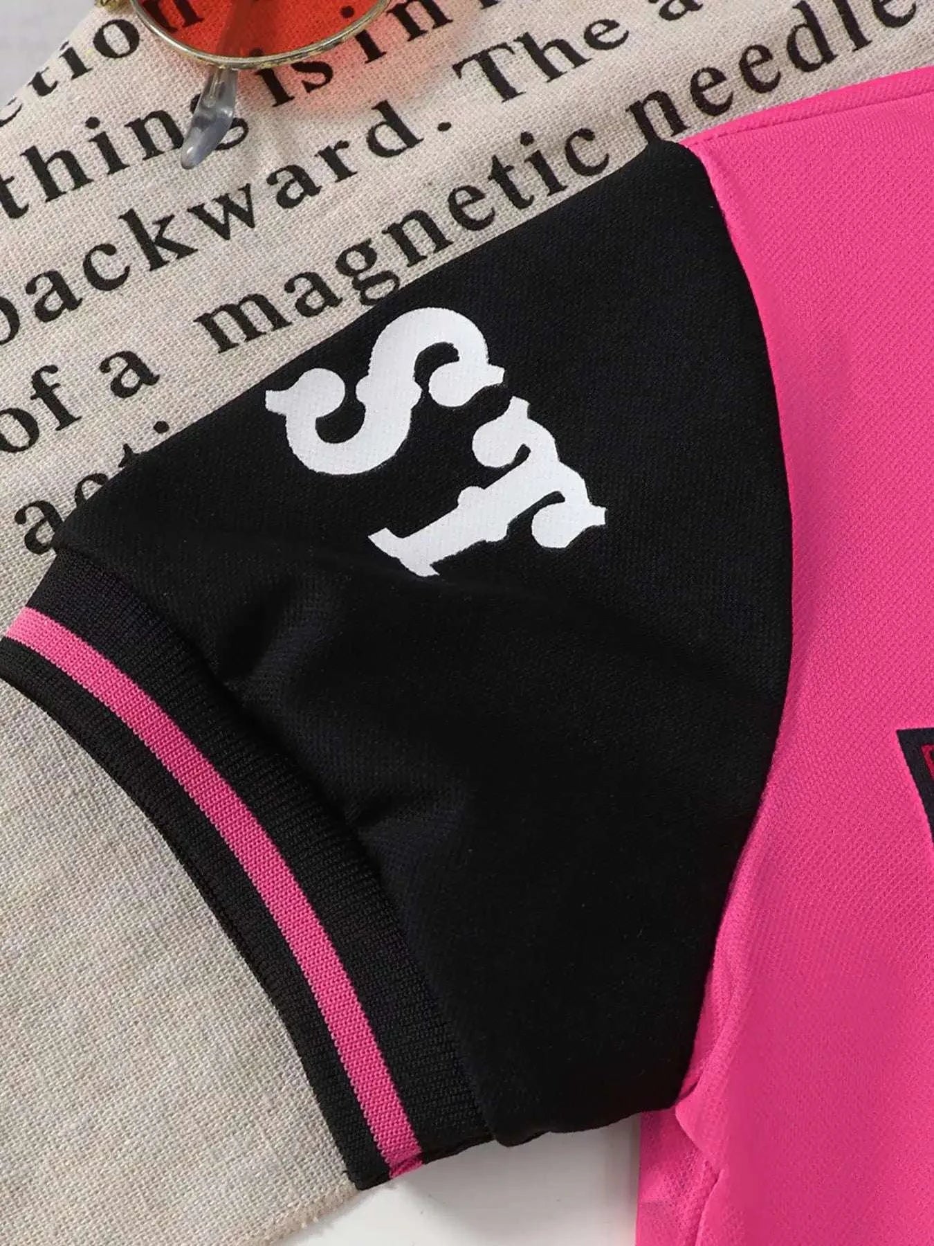 Kids black shorts close-up with white horse graphic and pink side stripe