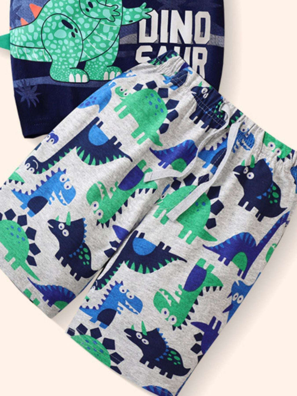 Kids patterned dinosaur shorts with blue, green, and navy dinos on light gray; tie waist
