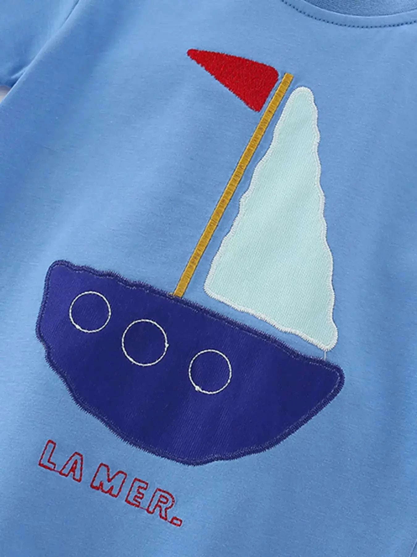 Sky blue children’s tee with sailboat graphic, navy sail, and CAMER text