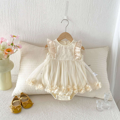 Cream baby tulle romper dress with ruffled yoke, flared skirt, and pom pom trim