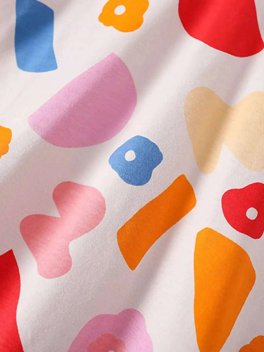 Children's printed round-neck top with multicolor patch motifs on light background