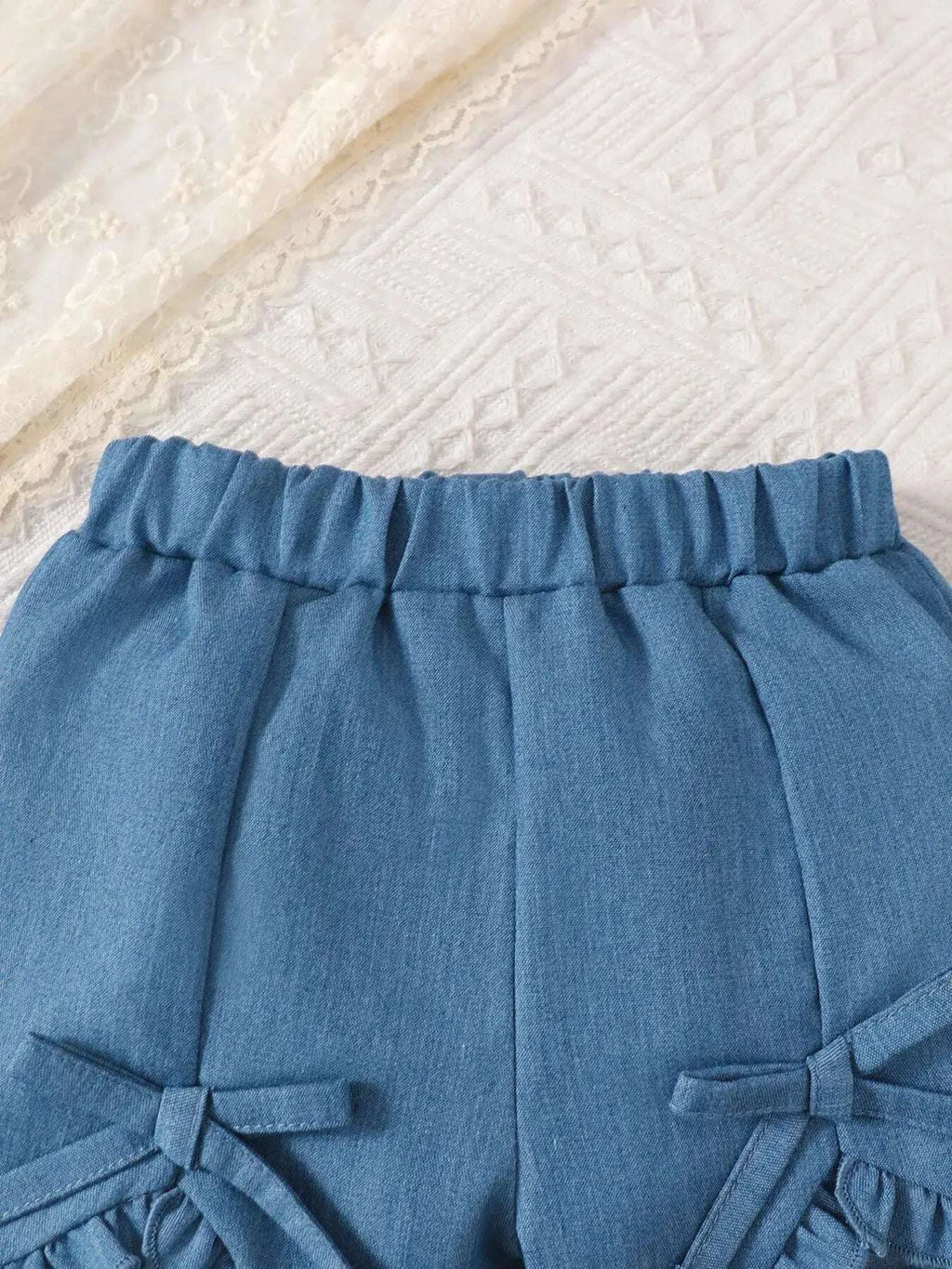 Blue ruffled waist shorts with bow accents at side seams