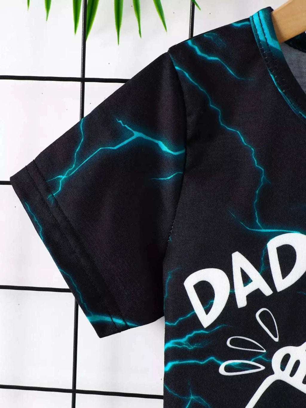 Black lightning print tee sleeve with turquoise lightning lines and partial “DAD”