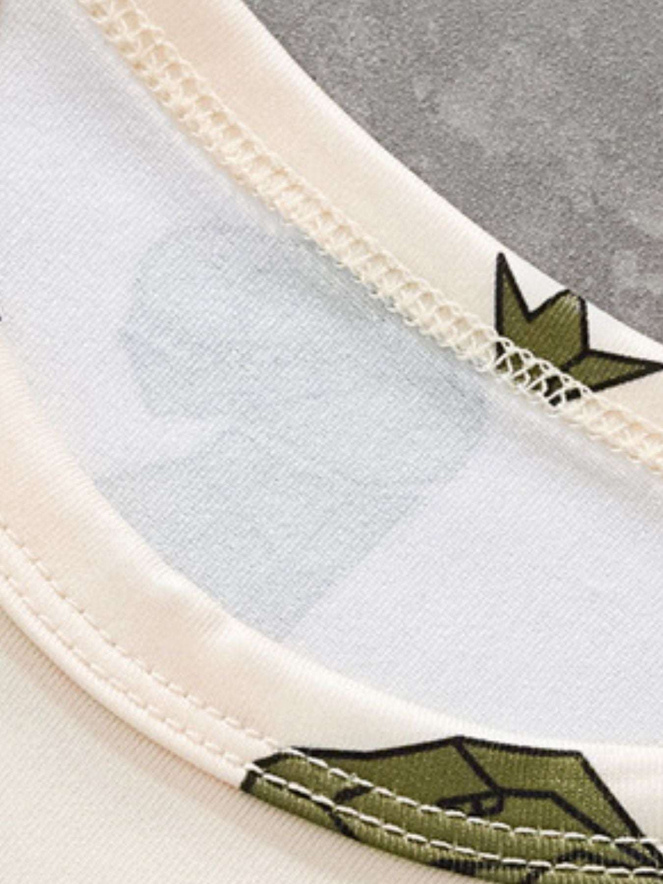Cream tee neckline and seam close-up with green dino print