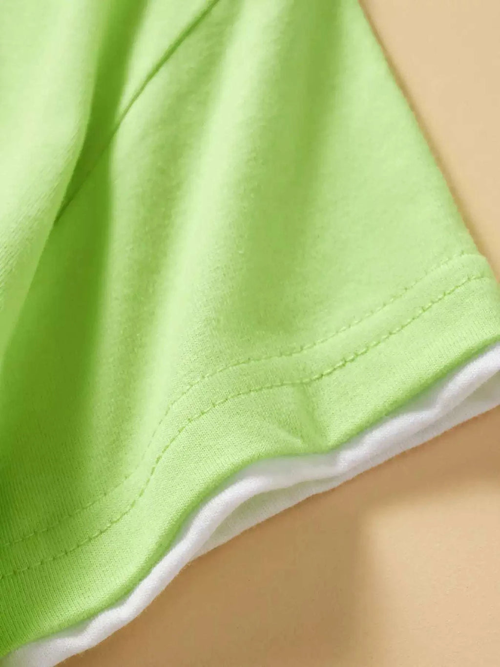 Neon green kids T-shirt side hem with double-stitched seam and white inner trim