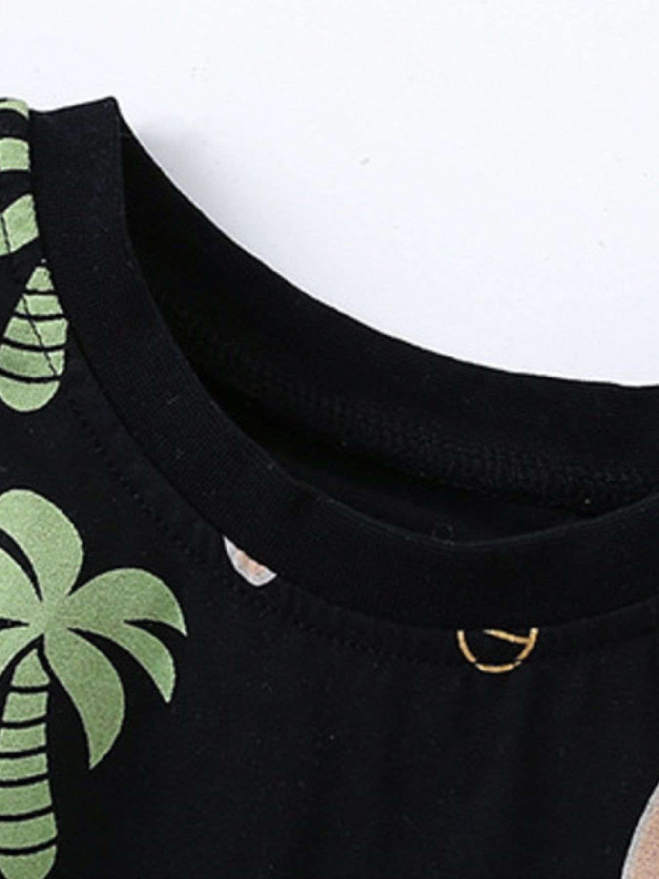 Black crew-neck tee with tropical palm and fruit print, close-up