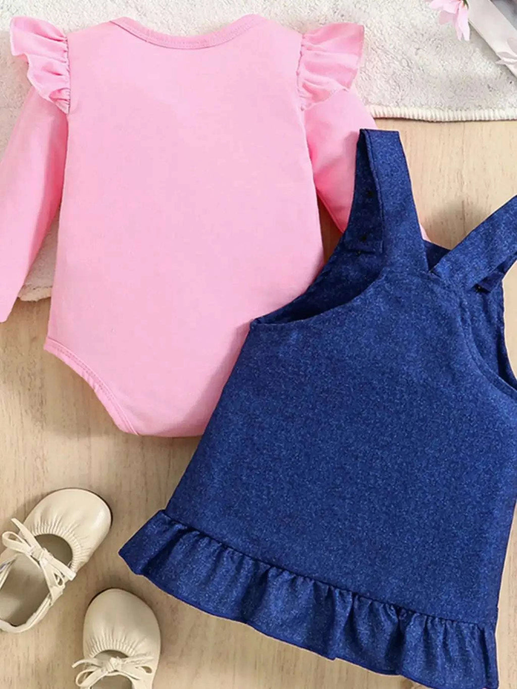 Pink long-sleeve bodysuit with ruffled cuffs and navy overall dress