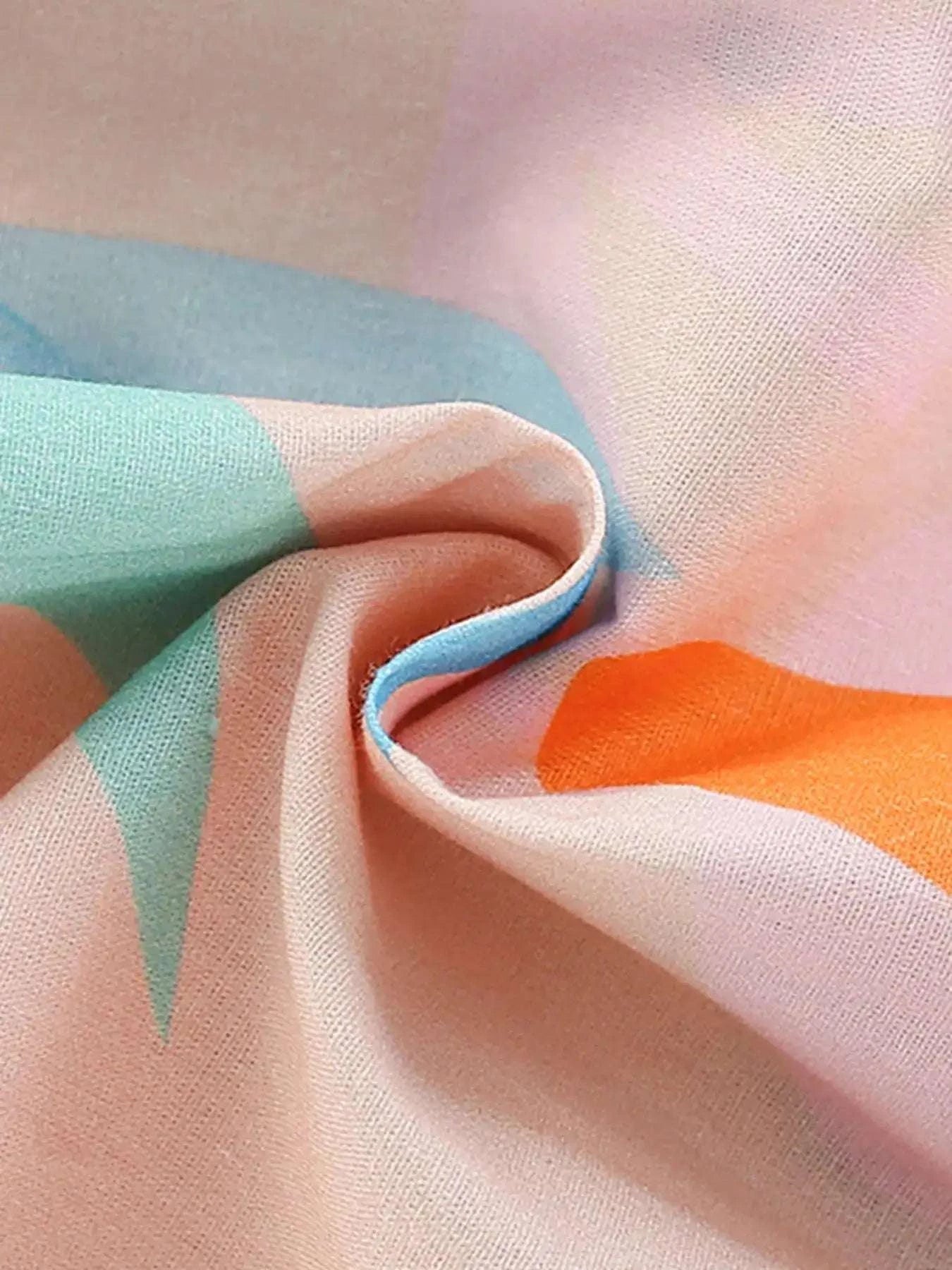 Tropical print fabric close-up with teal, orange, and pink swirls
