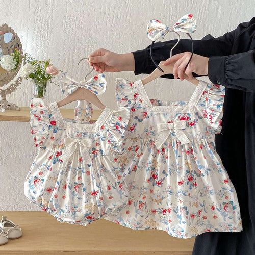 White floral baby romper dress with square neckline, ruffled sleeves, and waist bow