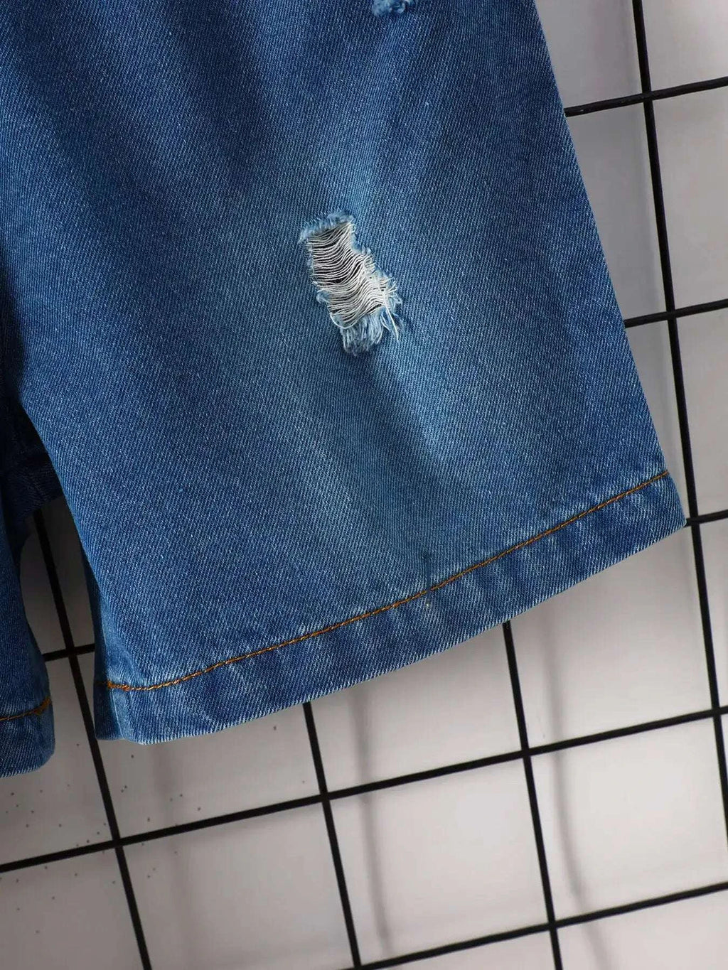 Blue denim shorts hem with stitching and small frayed tear
