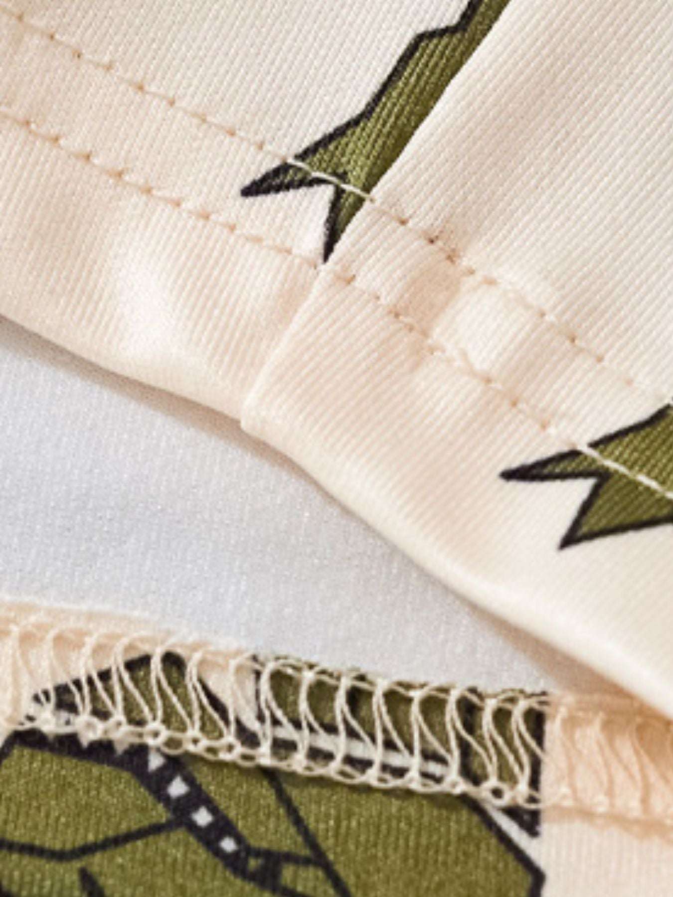 Cream shorts hem close-up with green dino print and stitched edge