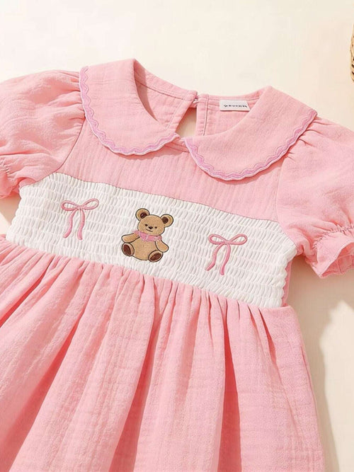 Pink smocked yoke dress with bear applique and bow embroidery on front