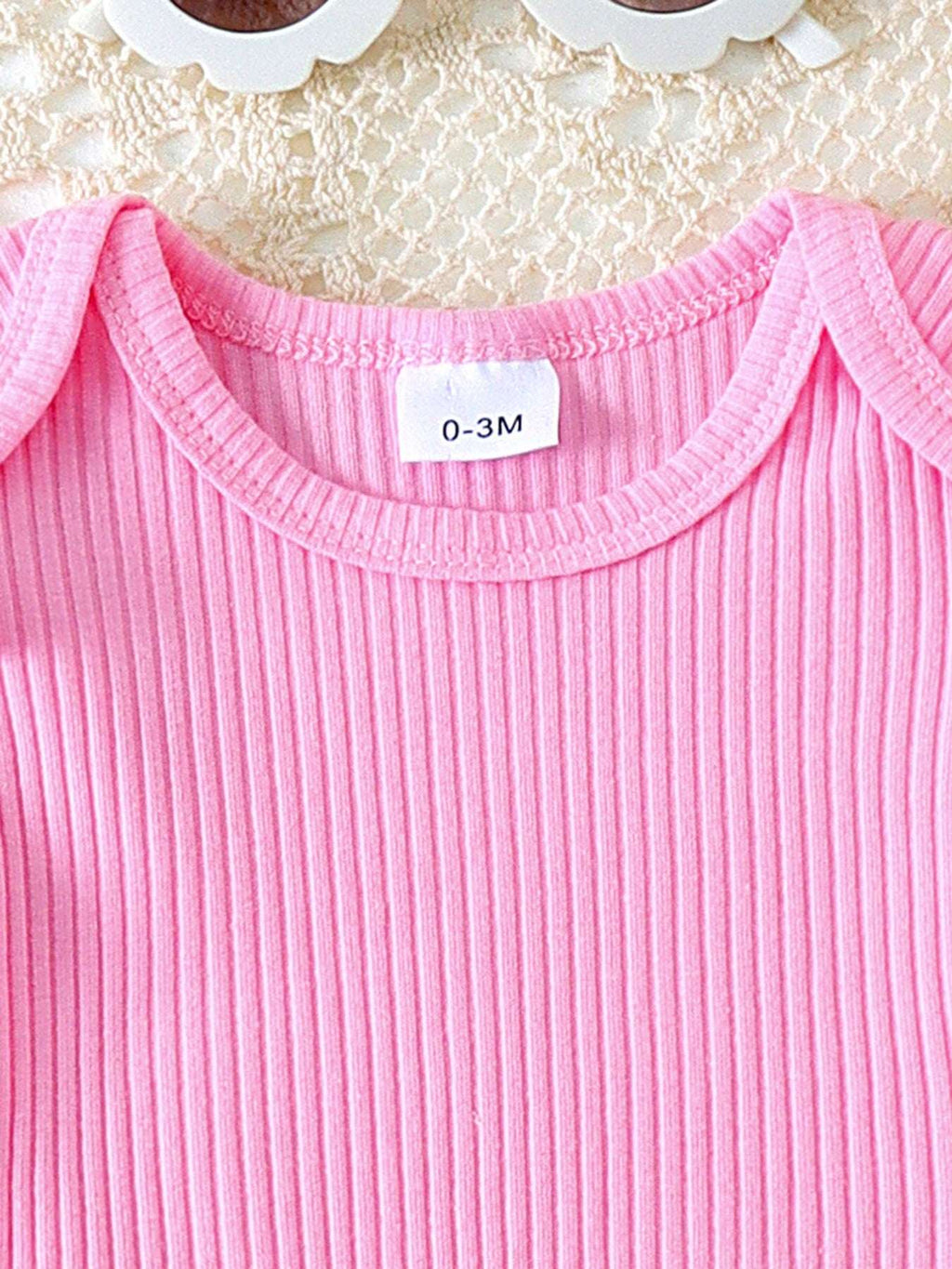 Pink ribbed knit top with ruffle trim and round neckline for baby