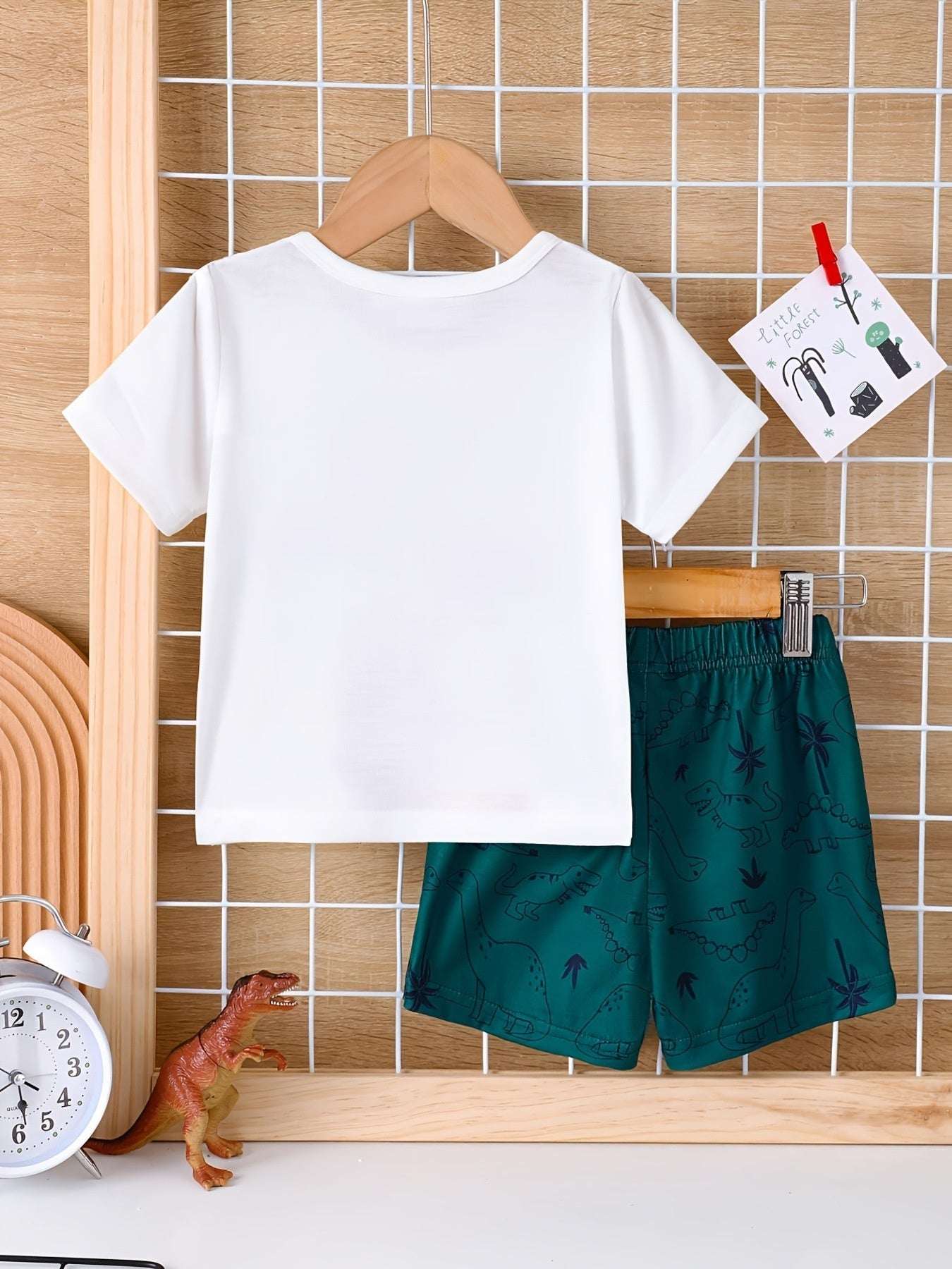 Kids white dinosaur tee and dark green dinosaur shorts set on hanger