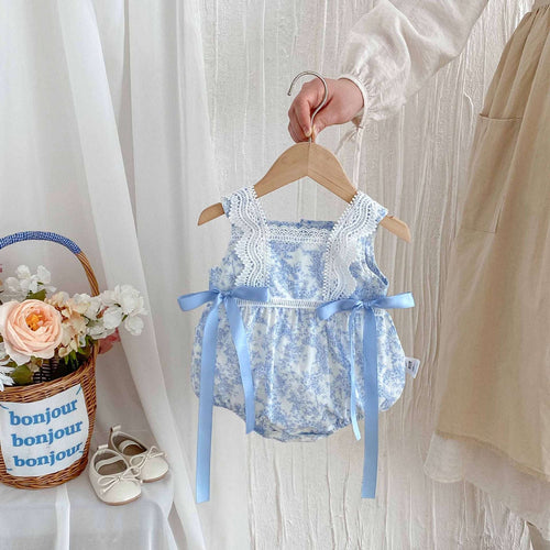 Blue floral newborn romper with lace trim and bow shoulder ties on a wooden hanger
