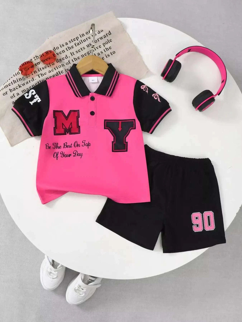 Kids rose pink polo shirt with black collar stripes, letter graphic; black shorts