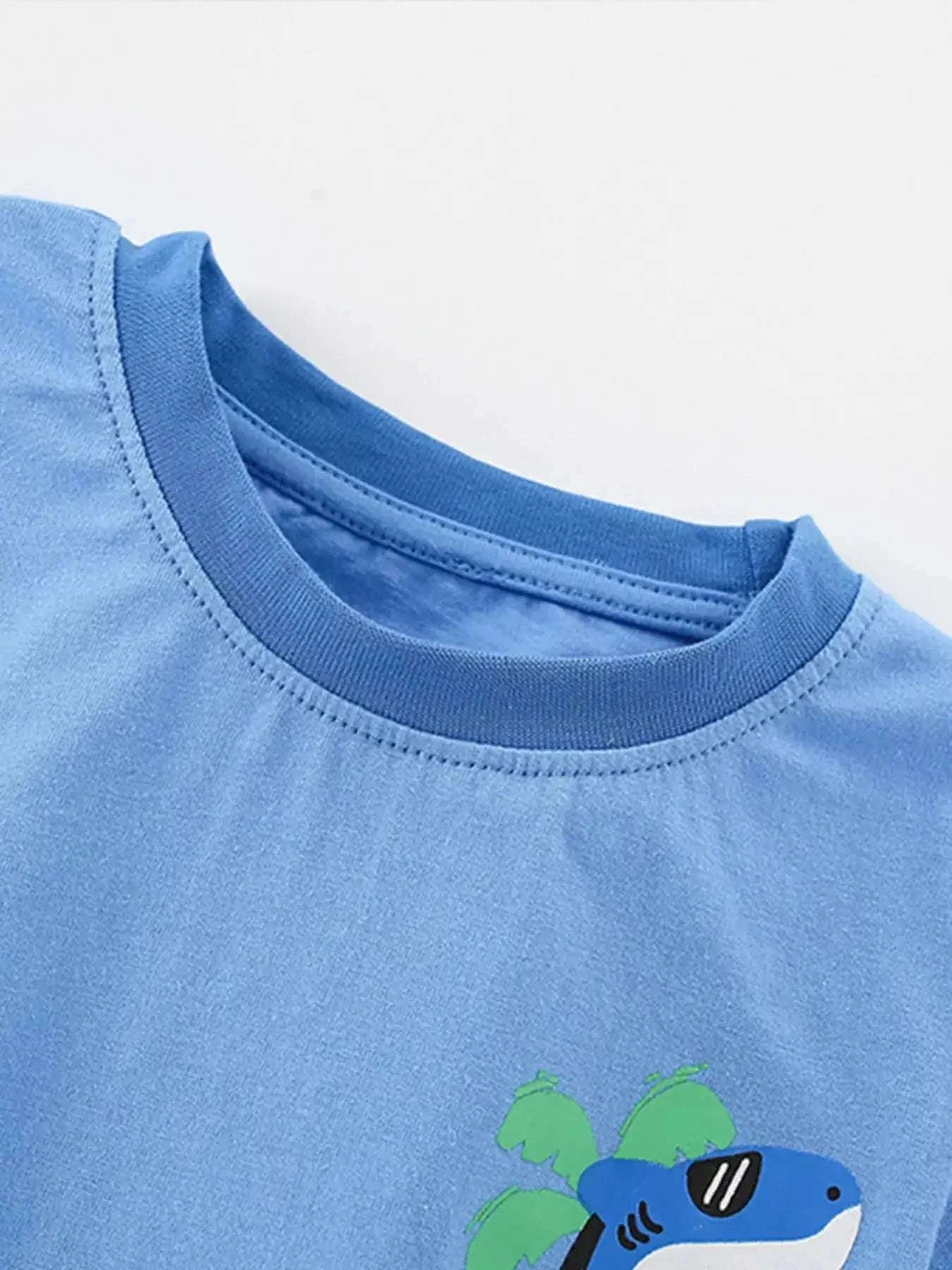 Sky blue kids tee with shark graphic and sea-sunsets text on chest