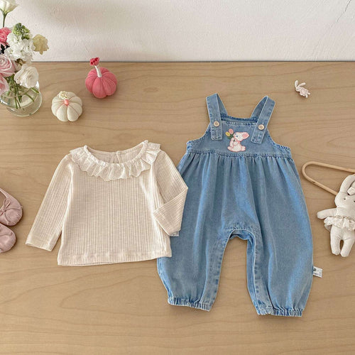 Blue denim overalls and cream long-sleeve ruffle top, flat lay baby outfit set