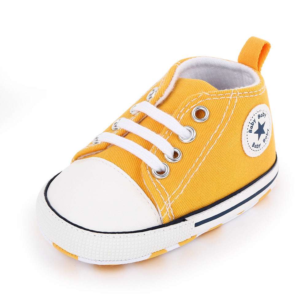 Baby canvas shoes in yellow with white toe, lace-up front, and star patch