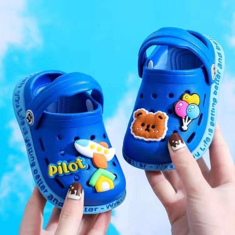 Blue kids' cartoon clogs held in hands with pig, fox, and other patches