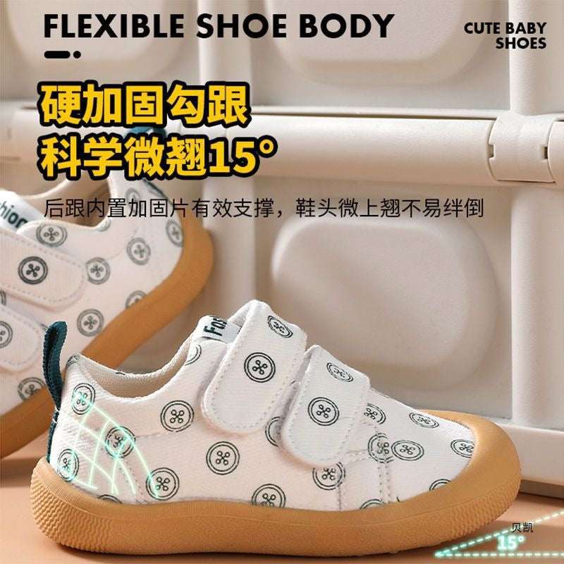 White cloth toddler shoes with circular pattern, teal pull tab, and tan non-slip sole
