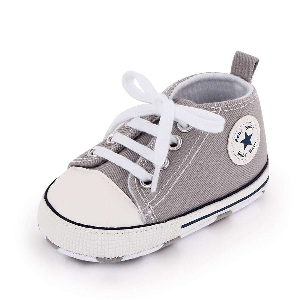 Baby canvas shoes in gray with white toe, lace-up front, and star patch on side