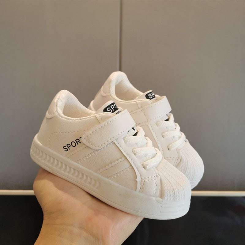 Baby velcro sneakers, light beige and white with gum sole, front side view in hand.