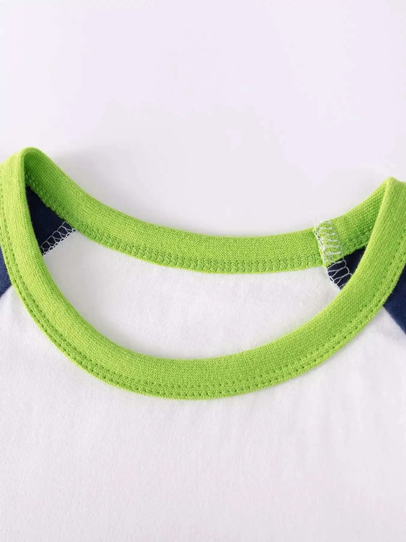 Ribbed green crew neckline on white children’s T-shirt with navy trim
