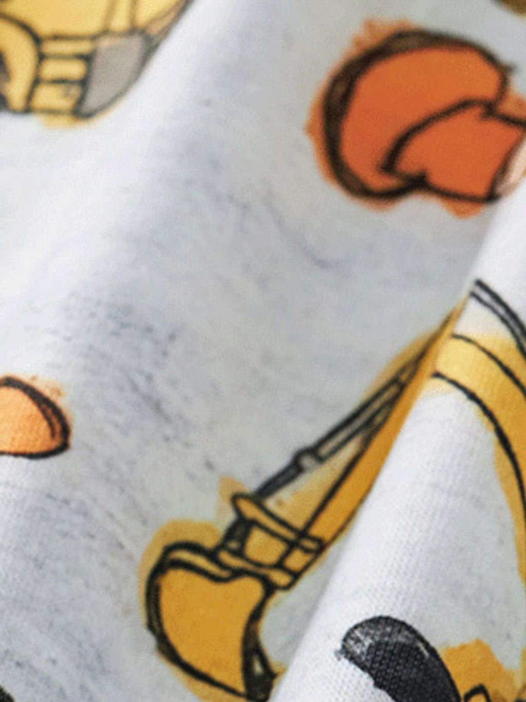 Kids tee close-up: white fabric with orange, yellow, and black construction vehicle print