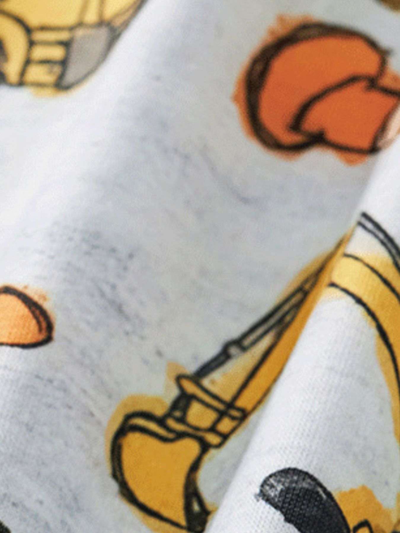 Kids tee close-up: white fabric with orange, yellow, and black construction vehicle print