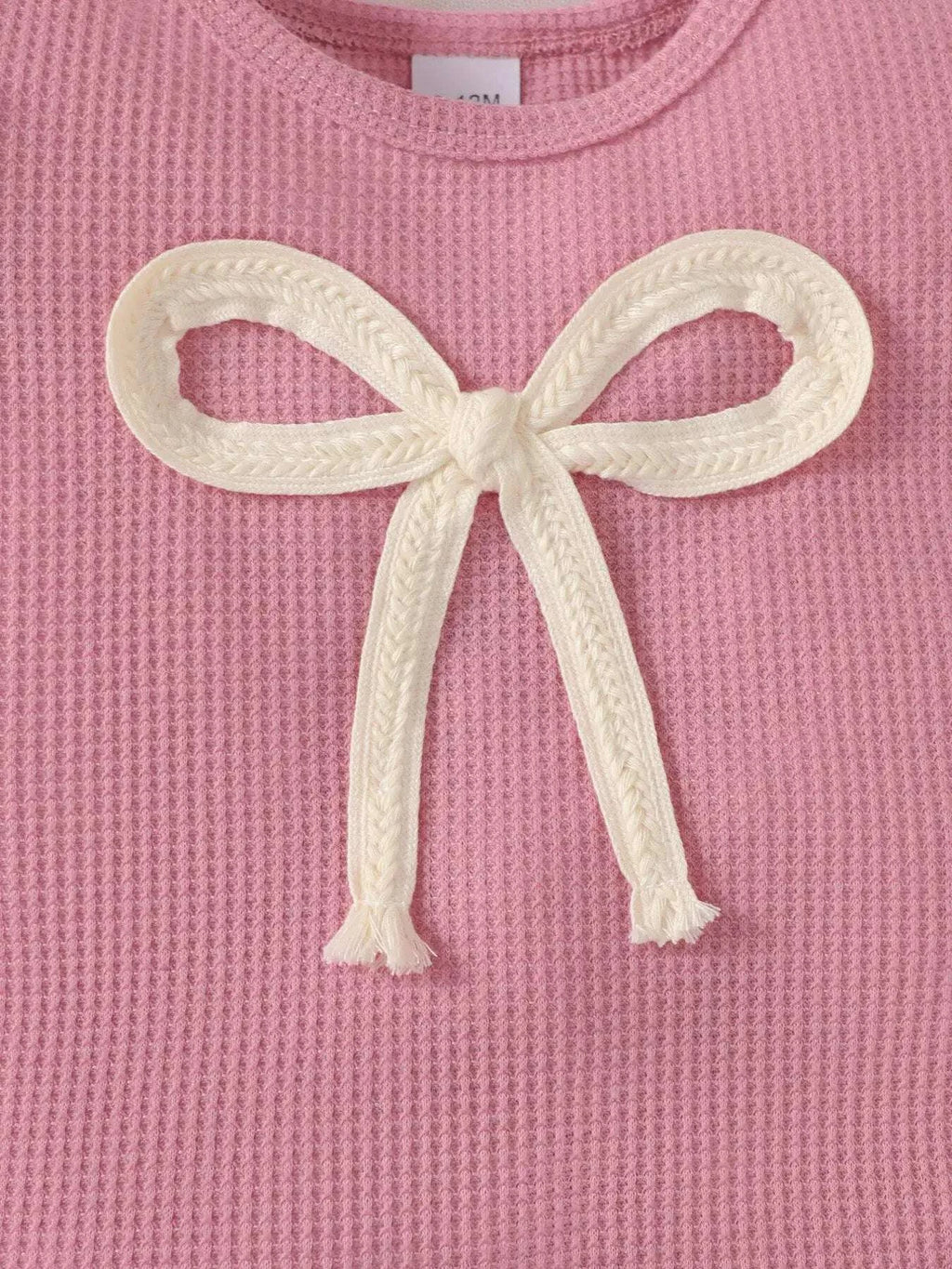 Pink knit top front with large white bowknot applique