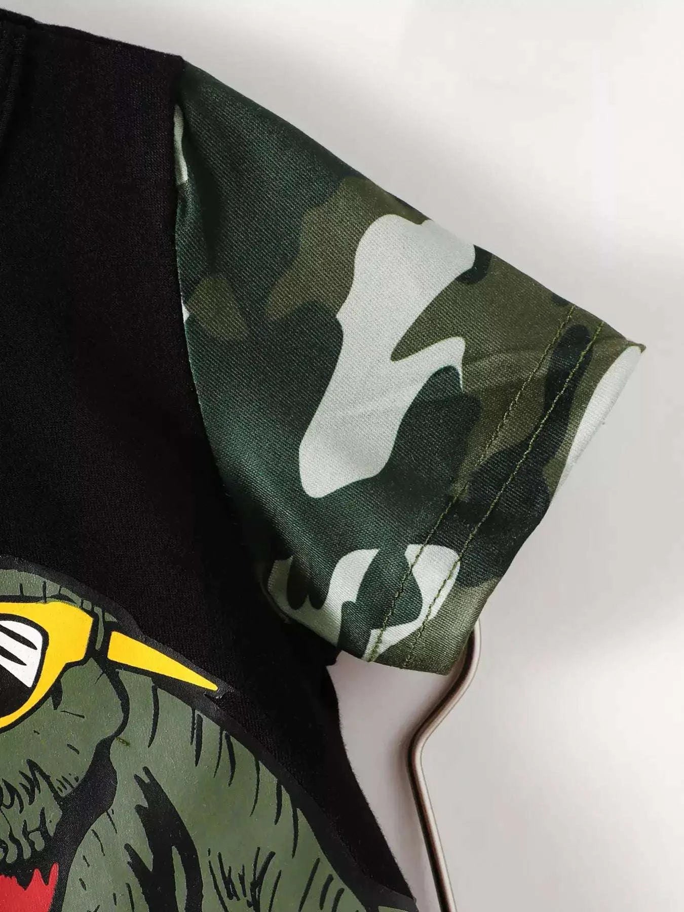 Green camouflage camo shorts with black trim, paired with black dinosaur graphic tee