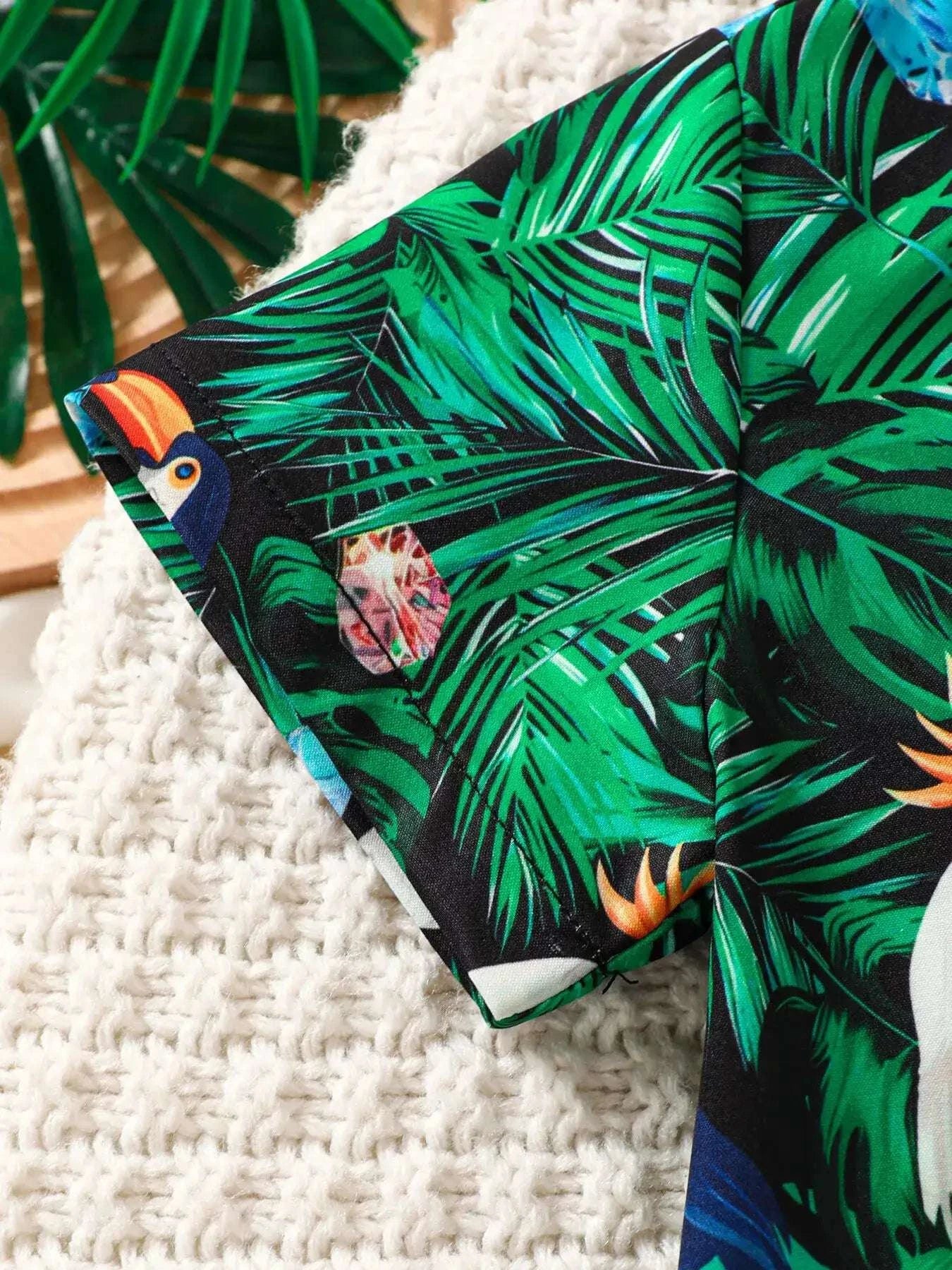Green tropical print shirt corner with collar, black bow tie, and white buttons.