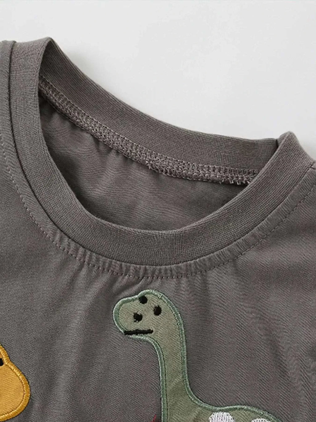 Dark gray children’s t-shirt with small dinosaur face applique at neckline