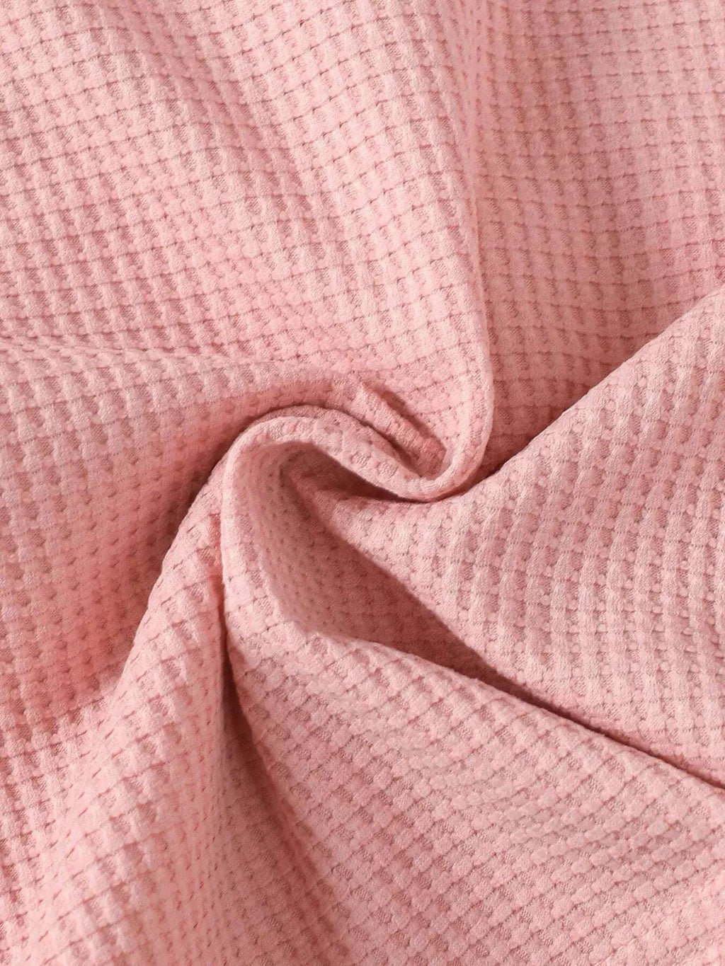 Pink waffle-knit fabric close-up with fine textured weave