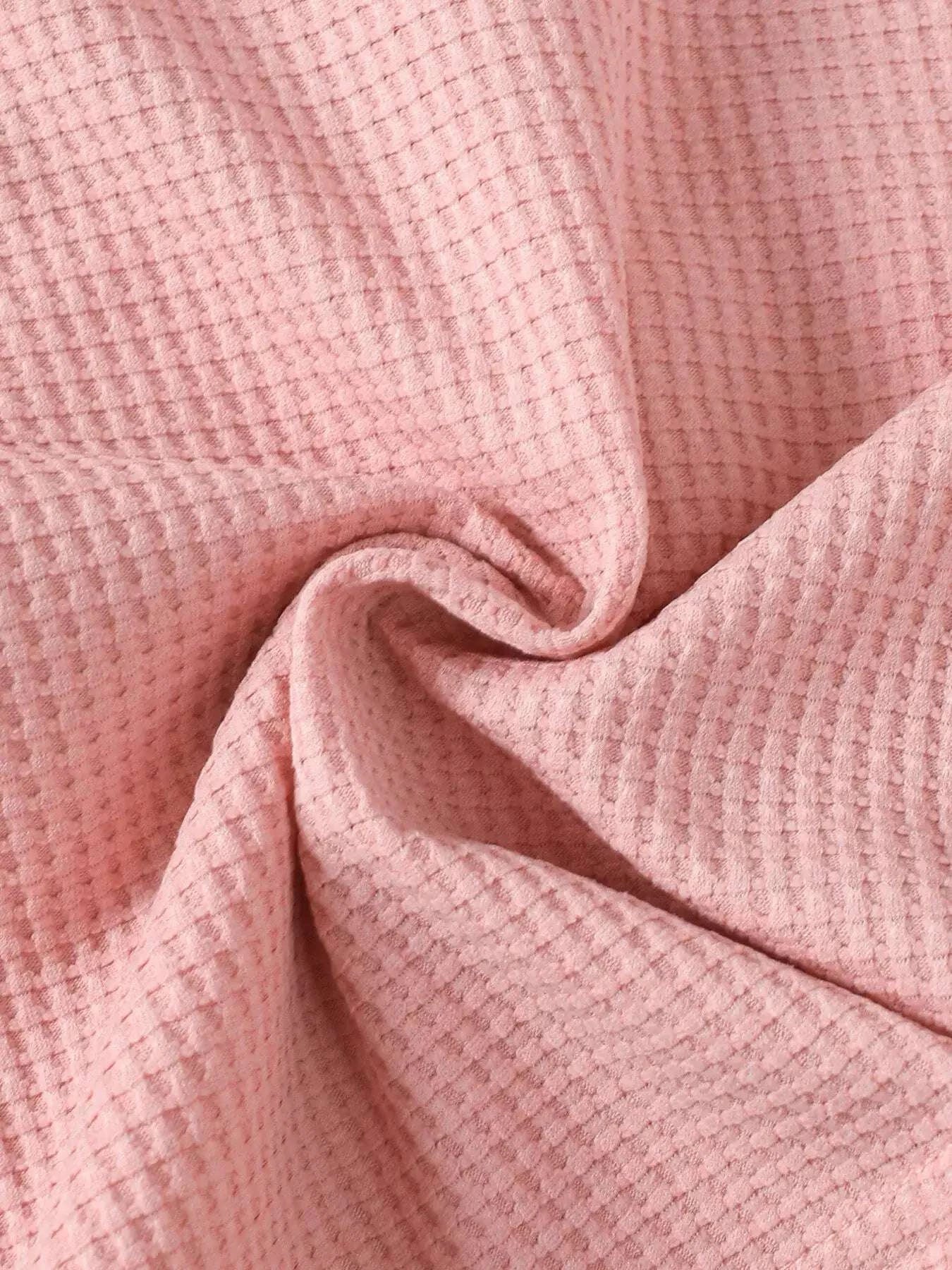 Pink waffle-knit fabric close-up with fine textured weave
