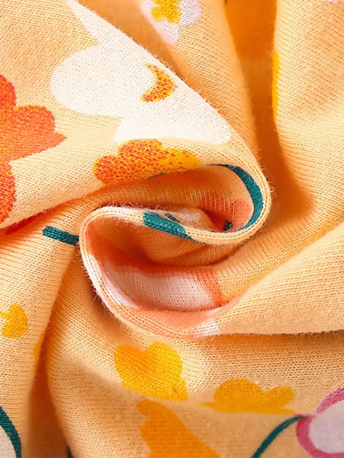 Kids floral jersey fabric close-up in yellow-gold with colorful blossoms and leaves