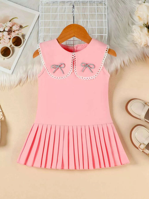 Pink bow-accented pleated dress on hanger with scalloped bib and bow details