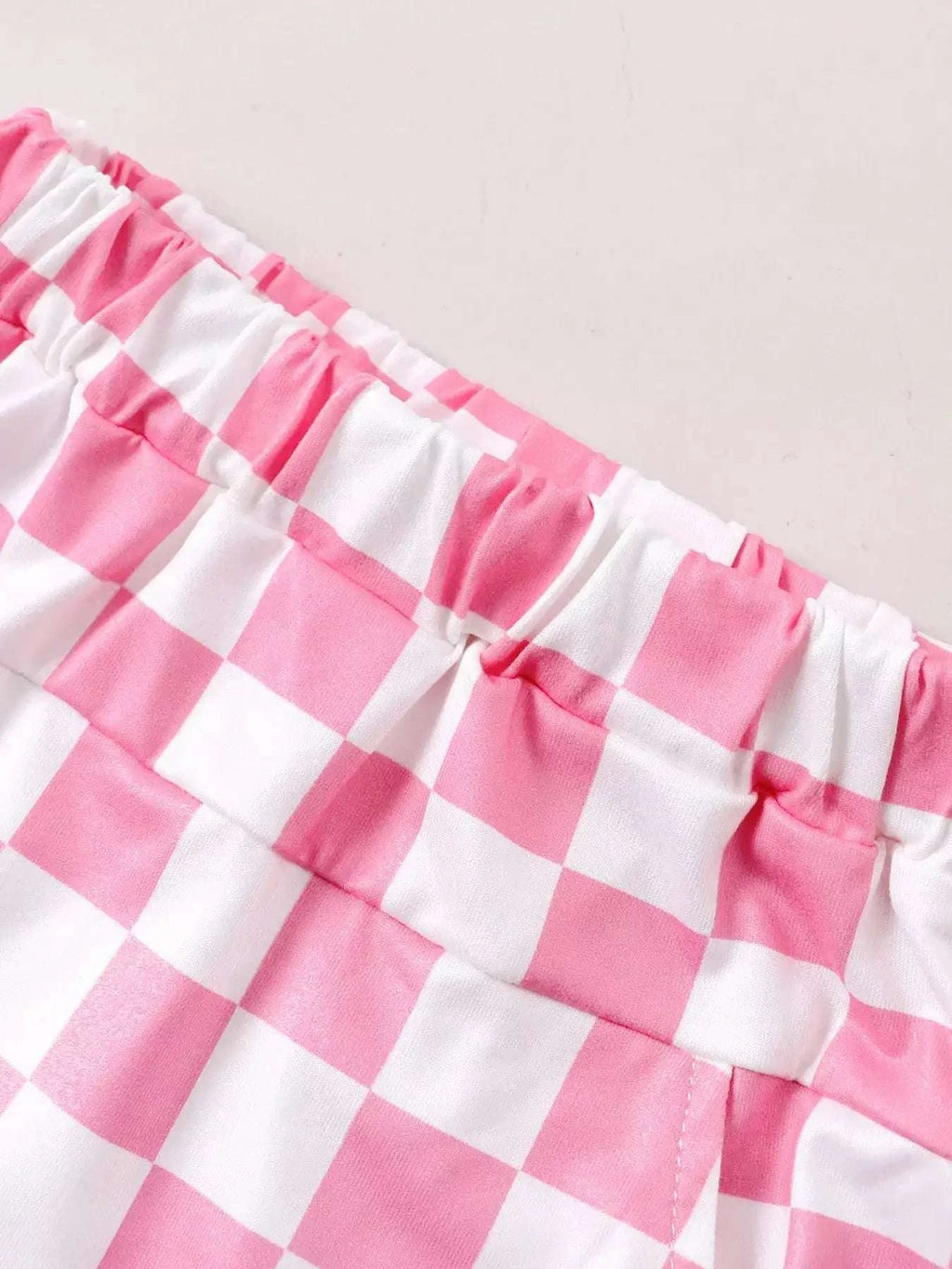 Kids pink-and-white checkered shorts with elastic waistband and tiered stitching