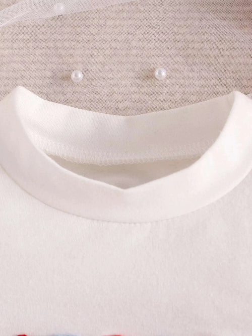 White toddler top with V-neck trim and two faux pearl button accents at the collar