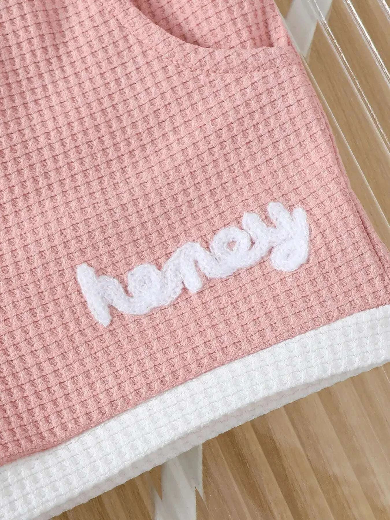 Pink waffle-knit shorts hem with white “honey” print and textured fabric