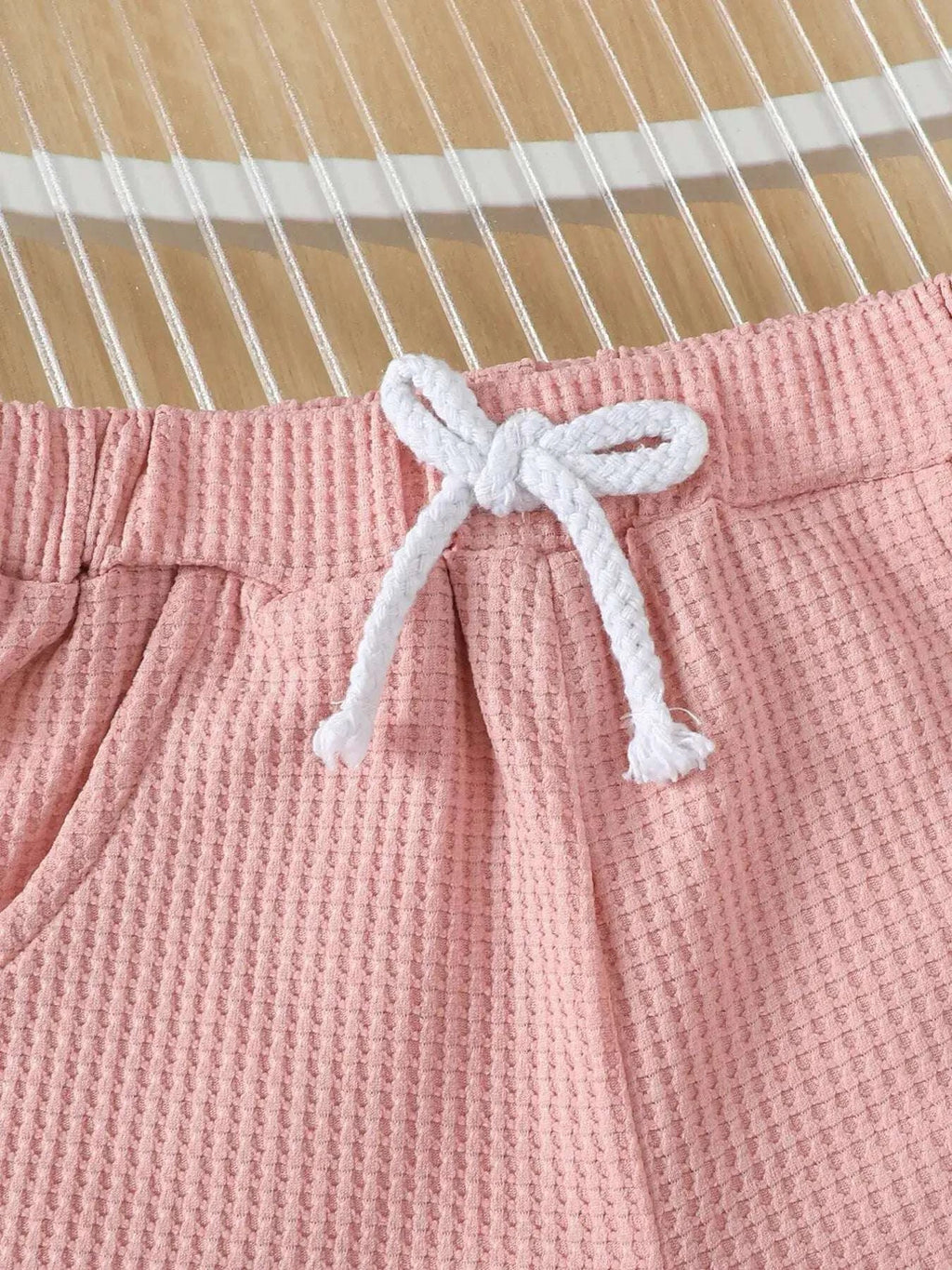 Pink waffle-knit shorts with white drawstring and gathered elastic waist