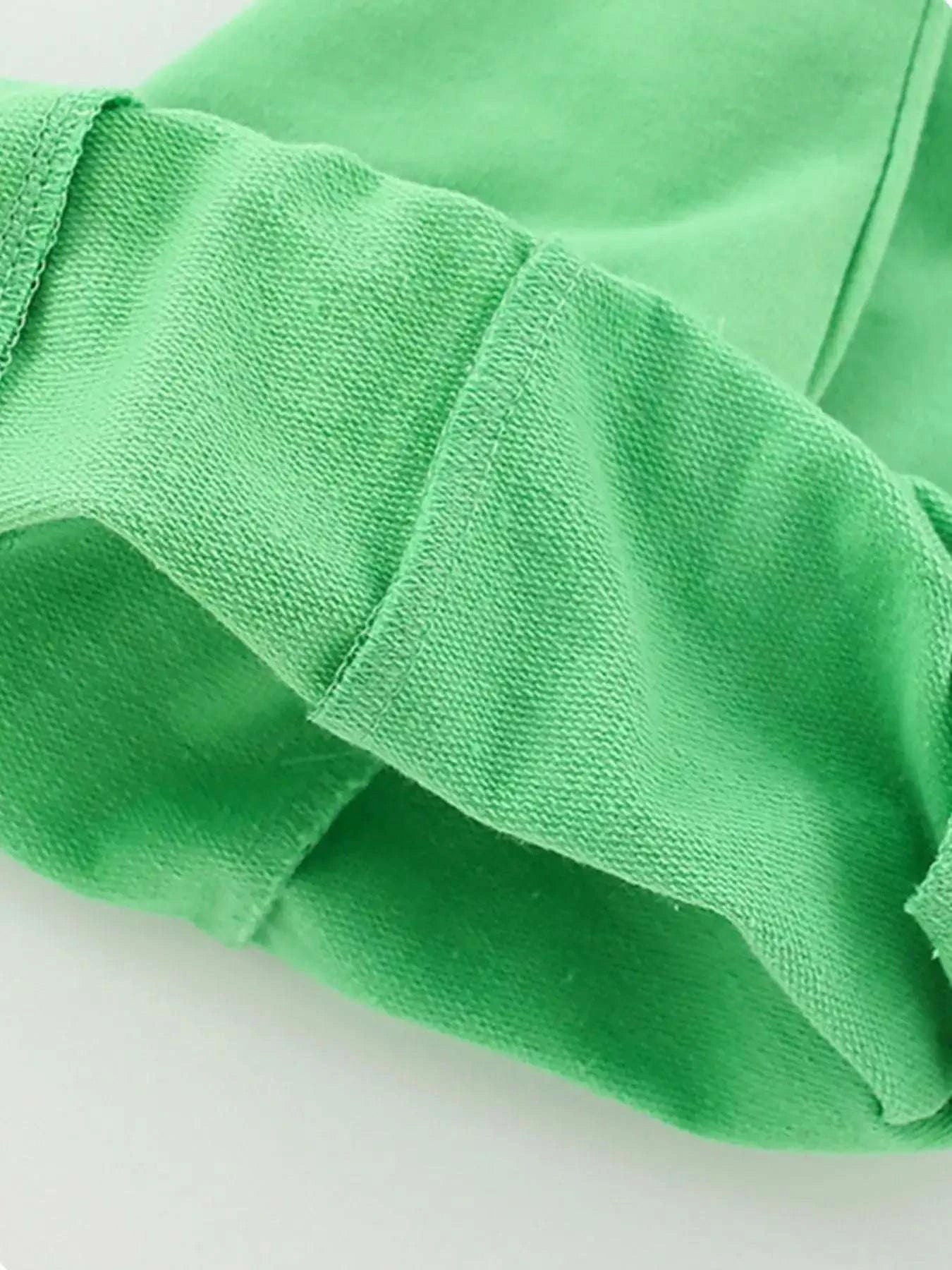 Green kids shorts fabric close-up with smooth knit texture