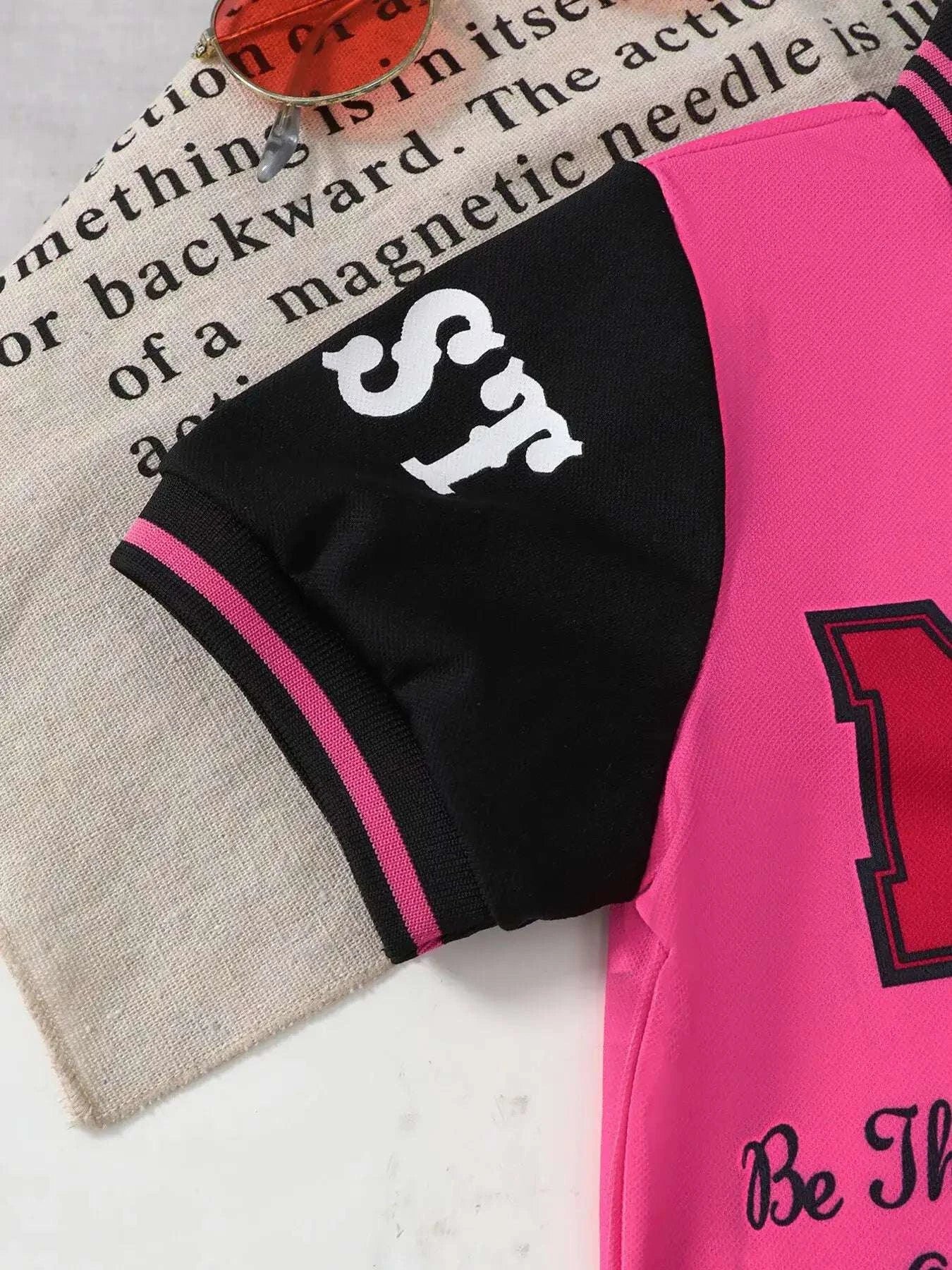 Kids black shorts with pink trim and white horse graphic; rose pink polo nearby